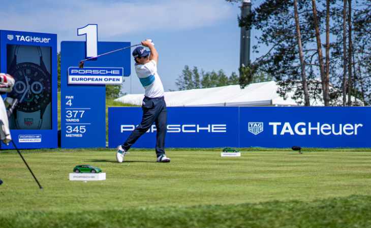 Ein Golfer schlägt vor Sponsorentafeln ab