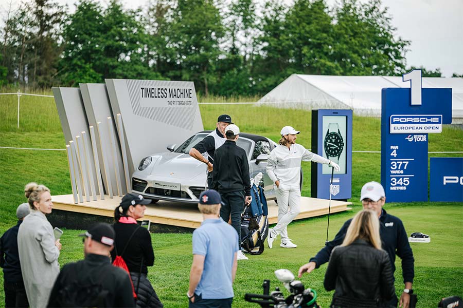 Tommy Fleetwood steht vor einem Porsche Wagen auf dem Porsche European Open im Freien