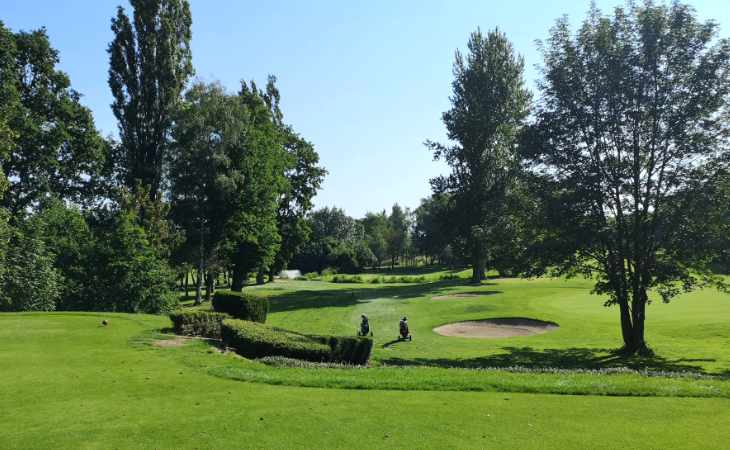 Zwei Trolleys, Hecken und Sandbunker auf einem Golfplatz