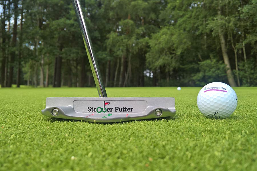 Der Straight Putter neben einem Golfball auf dem Rasen