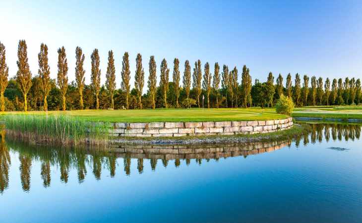 Ein angelegter Teich und eine Baumreihe auf einem Golfplatz