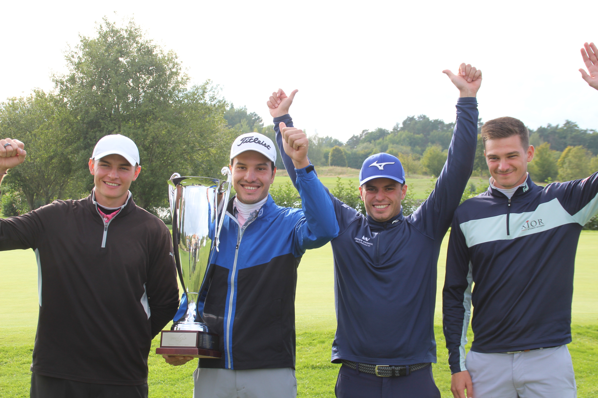 Vier Golfer auf einem Golfplatz, einer hält einen Pokal