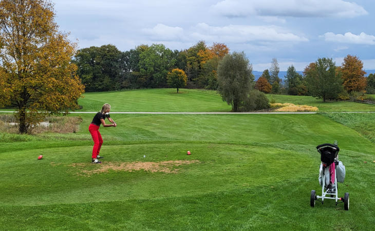 Eine Golferin schlägt auf einem Golfplatz ab