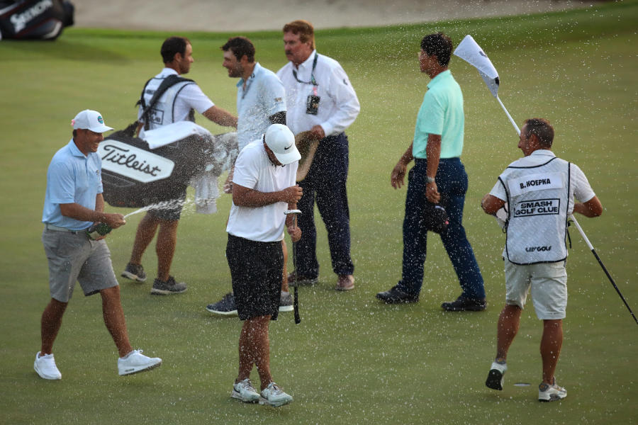 Brooks Koepka wird auf einem Golfplatz mit Champagner bespritzt