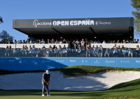 Ein Golfer vor einem Sandbunker, dahinter eine Zuschauer-Tribüne