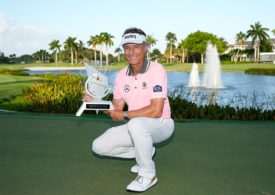 Bernhard Langer hockt vor einem Teich mit einem Pokal in seinen Händen