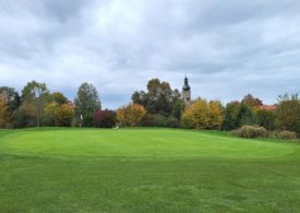 Ein Golfplatz und im Hintergrund ist eine Kirche