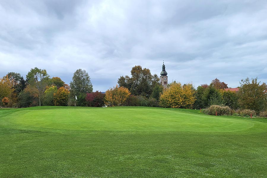 Ein Golfplatz und im Hintergrund ist eine Kirche