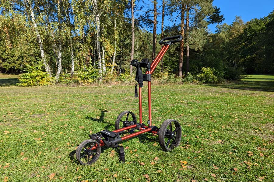 Ein roter Golfwagen steht auf einer Wiese