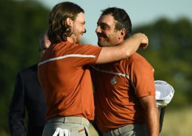 Zwei Golfer die sich umarmen und beide tragen ein orangenes Poloshirt