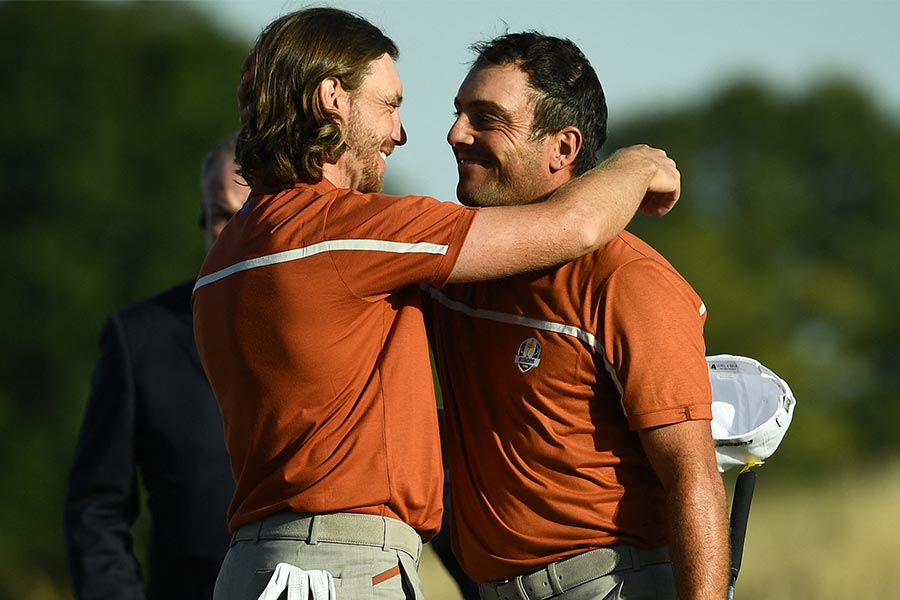 Zwei Golfer die sich umarmen und beide tragen ein orangenes Poloshirt