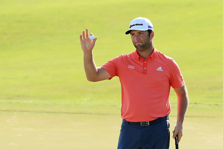 Der Golfspieler Jon Rahm hält ein Golfball hoch und guckt enttäuscht