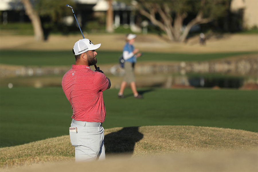 Der Golfspieler Jon Rahm hält einen Golfschläger hoch