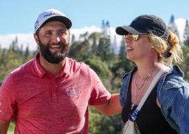 Links steht ein männlich Golfspieler in einem roten T-Shirt und rechts steht eine Frau in einer Jeans Jacke und hat eine Sonnenbrille auf