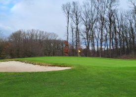 Ein Golf Feld mit einer Sandfläche auf der linken Seite und da steht ein Mann