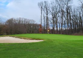 Ein Golf Feld mit einer Sandfläche auf der linken Seite und da steht ein Mann