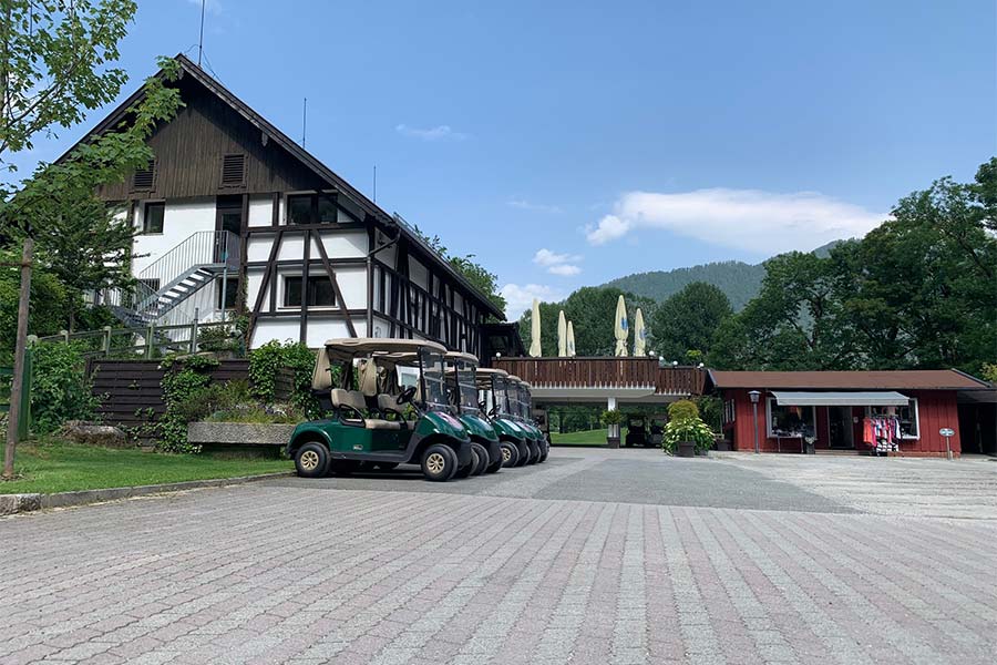 Mehrere Golfcars stehen vor einem Fachwerkhaus