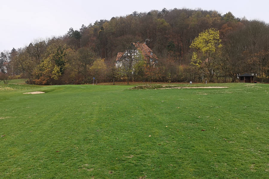 Ein Clubhaus hinter Bäumen auf einem Golfplatz