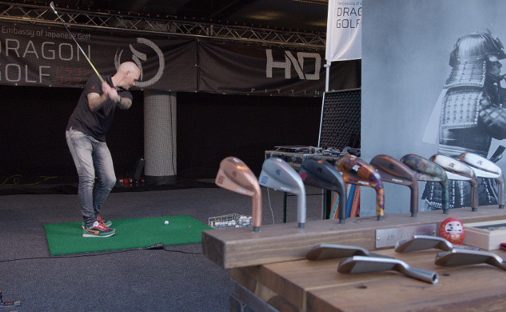 Ein Golfer schlägt am Messestand einer Golfmesse ab