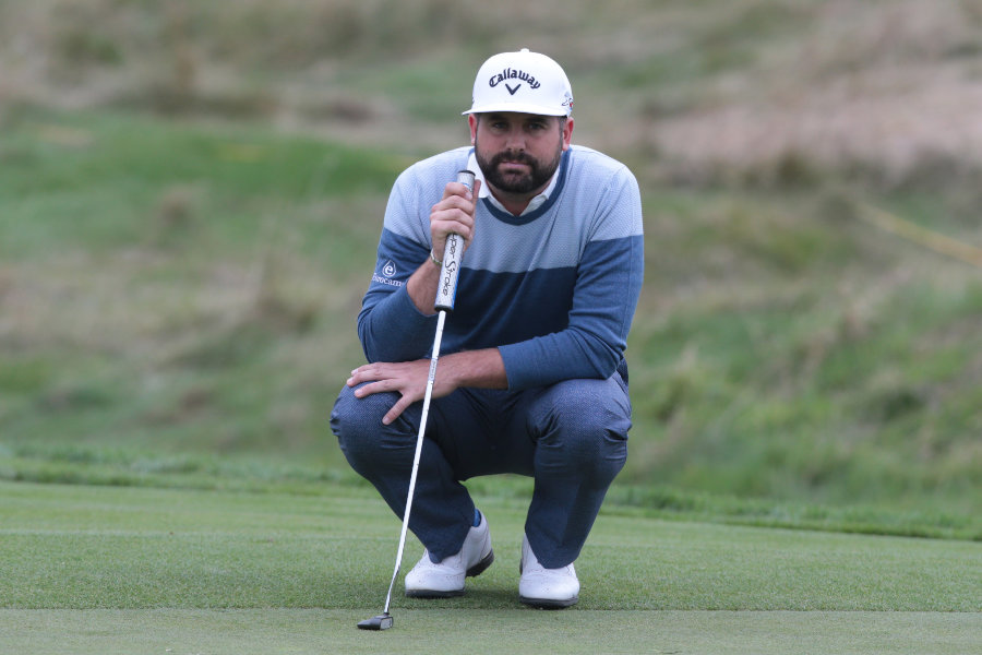 Ein Golfer hockt auf dem Green und überlegt