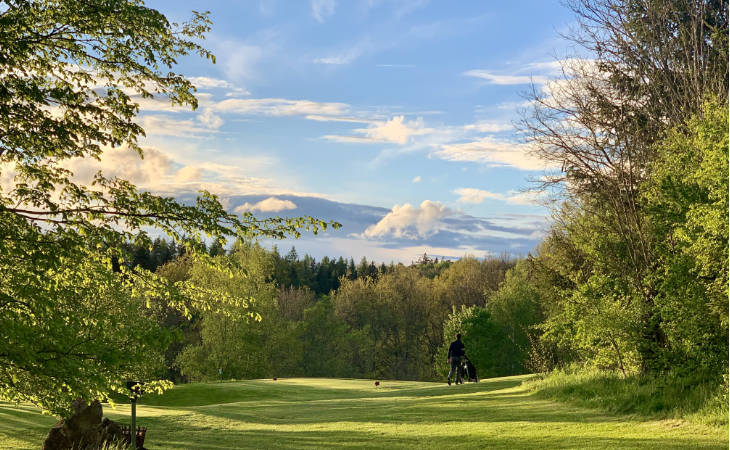 Ein Golfer auf einem schönen Golfplatz, im Hintergrund Bergpanorama