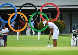 Ein Golfer puttet vor den olympischen Ringen