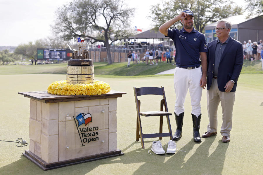 Golfer Corey Connors nimmt in Cowboy-Stiefeln eine Trophäe entgegen