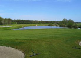 Eine Golfwiese mit einem Teich im Hintergrund