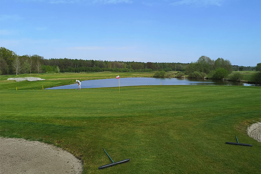 Eine Golfwiese mit einem Teich im Hintergrund