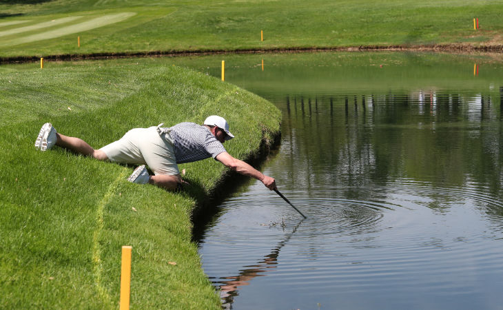 Ein Golfer versucht, einen Ball aus dem Wasser zu fischen