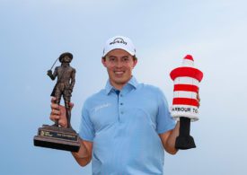 Der Golfspieler Matt Fitzpatrick hält in seiner rechten Hand ein Pokal und in der linken eine Art von Stofftier in der Form einer Pylone