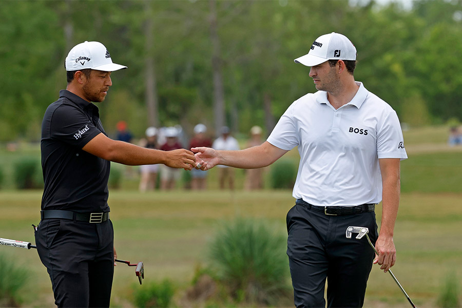 Die Golfspieler Xander Schauffele und Patrick Cantlay geben sich ein Handschlag und halten beide dabei ihren Schläger in der andern Hand