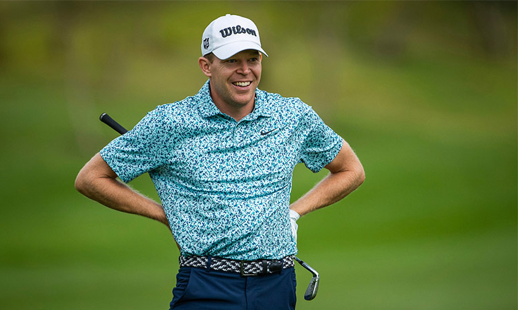 Der Golfspieler Alex Knappe lächelt und hat seine Hände an seiner Hüfte