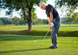 Ein älter Mann spielt Golf auf einer grünen Wiese