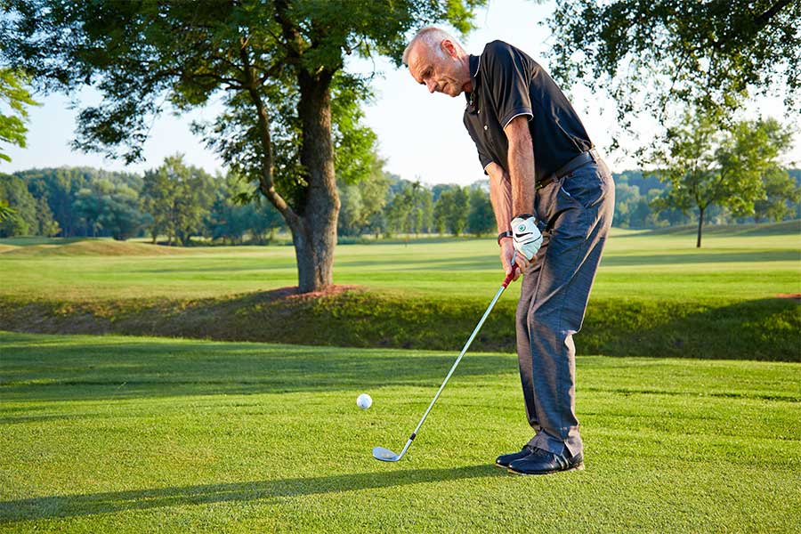 Ein älter Mann spielt Golf auf einer grünen Wiese