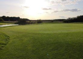 Eine Golflandschaft mit einem Sonnenuntergang im Hintergrund