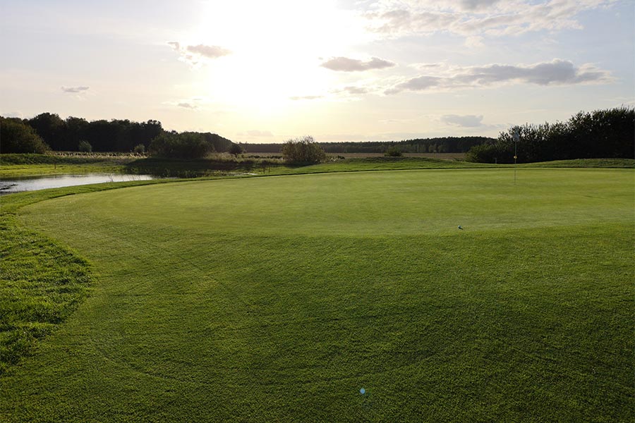 Eine Golflandschaft mit einem Sonnenuntergang im Hintergrund