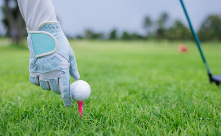 Ein blauer Damen-Golfhandschuh und ein Golfball