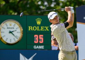 Ein Golfer beim Abschlag vor einer Rolex-Tafel