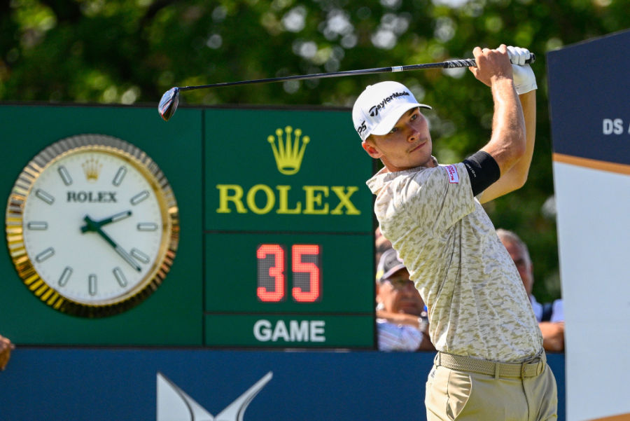 Ein Golfer beim Abschlag vor einer Rolex-Tafel