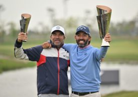 Ein Golfer und sein Caddie hieven Trophäen in die Luft