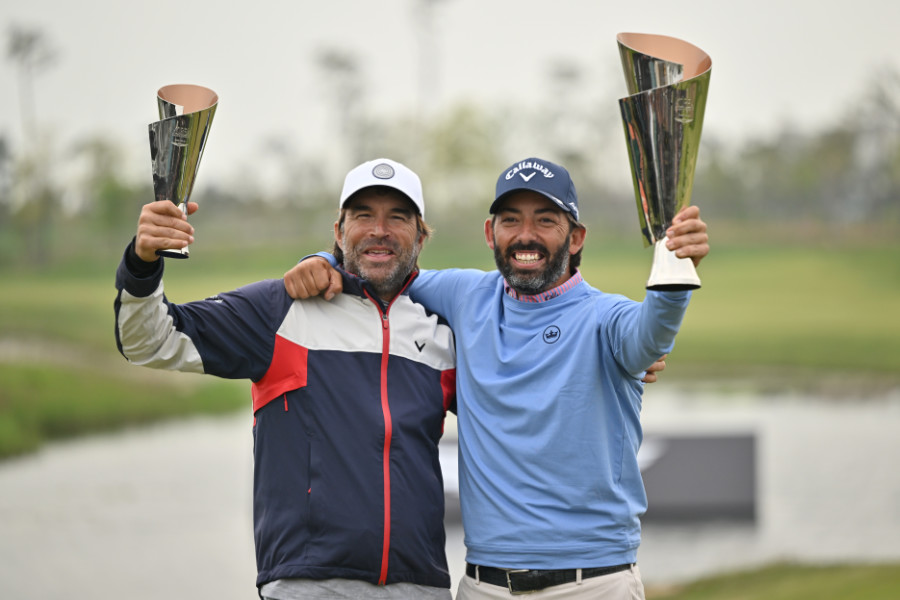 Ein Golfer und sein Caddie hieven Trophäen in die Luft