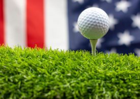 Ein Golfball auf einem Tee vor der Flagge der USA