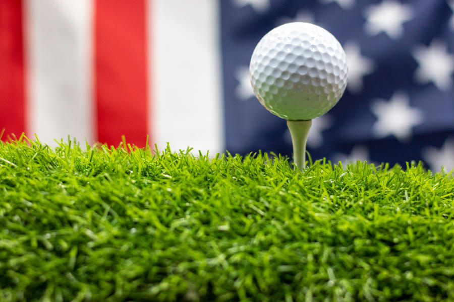 Ein Golfball auf einem Tee vor der Flagge der USA