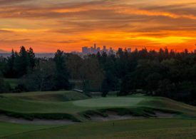 Ein Golfplatz vor einer Skyline im Abendrot