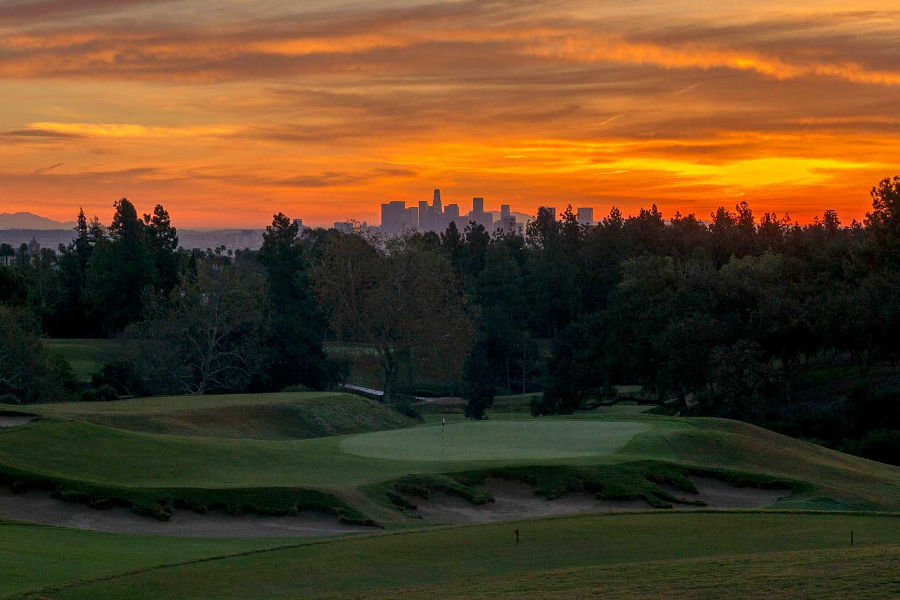 Ein Golfplatz vor einer Skyline im Abendrot