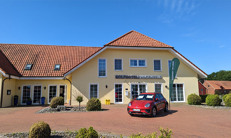 Ein Golfclub Gebäude mit einem roten Auto im Vordergrund