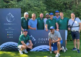 Zehn Golfer die vor einem Bild stehen und ein Gruppenbild machen