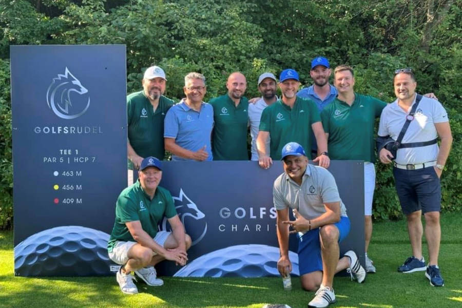 Zehn Golfer die vor einem Bild stehen und ein Gruppenbild machen