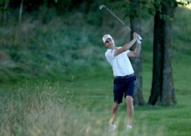 Ein Golfer schlägt nahe dem Rough mit dem Eisen